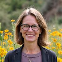 Sarah smiling amongst a newly planted wildflower meadow on a previously eroded slope.